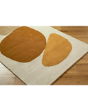 Modern beige area rug with large irregular brown and gold shapes on wooden floor