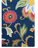 Close-up of luxury handwoven floral rug with vibrant red, yellow, green, and blue patterns on a navy background