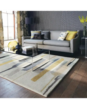 Modern living room with abstract patterned rug in beige, gold, and gray, gray sofa, decorative pillows, and geometric wallpaper
