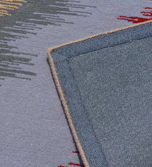 Close-up of modern abstract wave rug with gray and red patterns, showing woven edge detail
