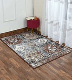Vintage-style area rug with geometric floral patterns in brown, cream, and black on wooden floor beside sheer white curtains and a red stool