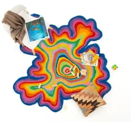 Irregular hand-tufted multicolor rug with vibrant concentric layers, styled with a beige throw, books, and a patterned pillow