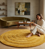 Woman sitting on a yellow circular rug in a modern living room.