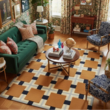 Living room with green sofa, patterned rug, and decorative items.