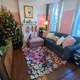 Cozy living room with a gray sofa, pink ottoman, colorful floral maximalist rug, and decorated Christmas tree
