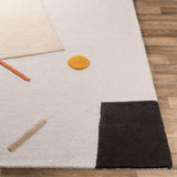 Modern wool rug with geometric shapes in black, beige, orange, and yellow on wooden floor