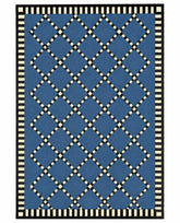 A rectangular area rug with a blue field featuring a cream-colored diamond lattice pattern, finished with a black and cream striped border.