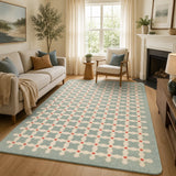 A large rectangular area rug with a light blue, cream, and coral-red geometric lattice pattern, shown in a styled living room setting with a sofa, armchair, and fireplace.