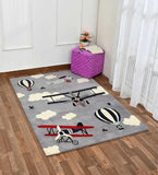 Handwoven wool rug with airplanes, hot air balloons, and clouds design on wood floor in bright room
