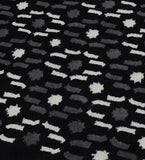 Close-up of black rug with white and gray abstract geometric patterns