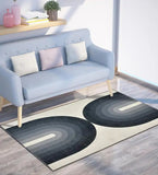 Modern geometric area rug with black and gray arch patterns on wood floor under light blue sofa