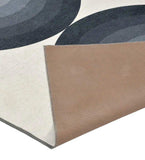 Modern geometric rug with black, gray, and white circular arches, corner flipped to show brown backing