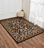 Black traditional hand-tufted wool rug with floral patterns on wooden floor near white wall and sheer curtains