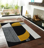 Modern black, white, and mustard yellow geometric handwoven rug on wooden floor in bright living space