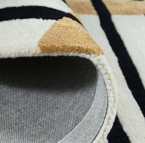 Hand-tufted wool rug in black, white, and mustard yellow design.