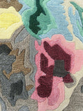 Close-up of Bloomburst hand-tufted wool rug with abstract floral pattern in pink, green, blue, yellow, and brown