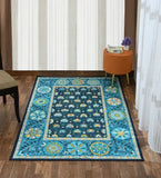 Blue medallion rug with floral patterns on wooden floor, next to orange ottoman and beige chair