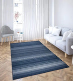 Modern living room with a blue striped rug on wood parquet floor, gray sofa with white pillows, and striped accent chair