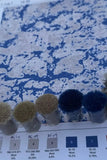 Blue and beige abstract pixel wool rug design with color yarn samples on testing chart