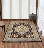 Blue and beige traditional floral area rug on wooden floor with gray ottoman and cup