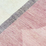 Close-up of a hand-knotted blush pink rug with scalloped design and gray and white borders