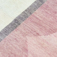 Close up of texture of Hand-knotted blush pink rug with scalloped border, crafted from wool.
