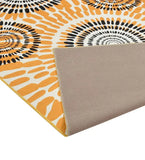 Close-up of a boho sunburst rug with orange and black radiating pattern and beige backing