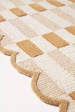 Close-up of a luxury handwoven brown checkered rug with scalloped edges from Mannat Rugs