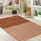 Brown geometric striped rug in light modern living room with potted plants and cozy seating