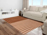 Modern living room with beige sofa and brown geometric striped rug on wooden floor