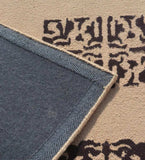 Close-up of camel hand-tufted rug with abstract dark brown patterns and blue backside edge