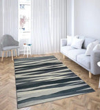Modern living room with charcoal grey abstract striped rug, light gray couch, striped chair, and wooden parquet floor