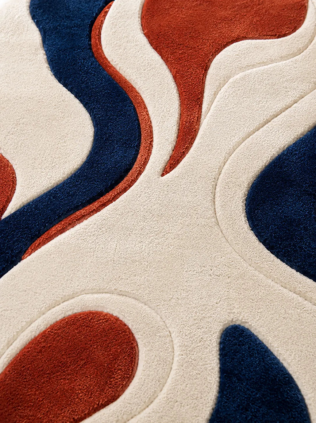 Close-up of a rug with wavy patterns in blue and red on a beige background