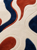 Close-up of a rug with wavy patterns in blue and red on a beige background