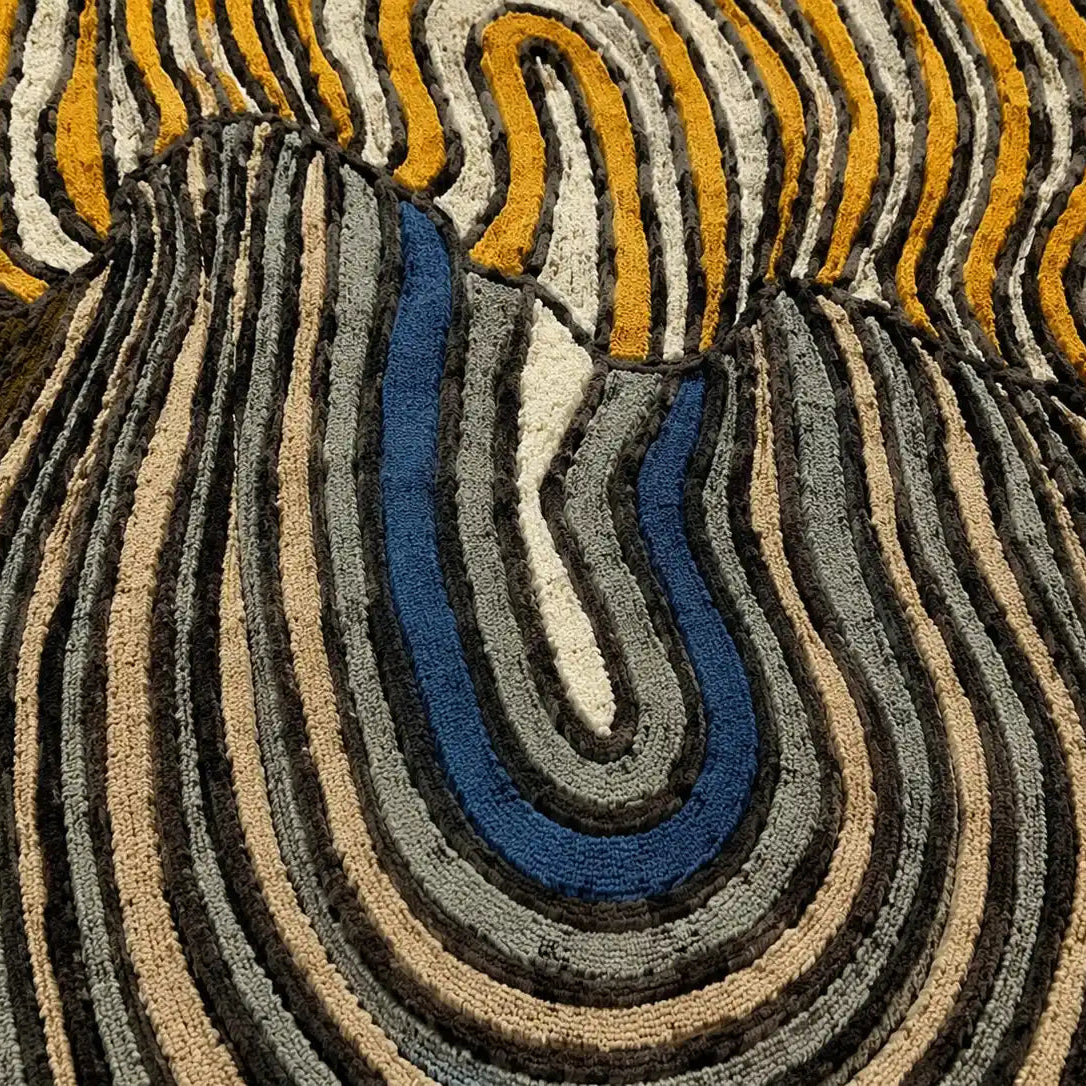 Close-up of a textured rug with wavy pattern in earthy tones.