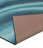 Close-up of luxury handwoven coastal blue abstract ocean rug with soft waves pattern and stitched edge