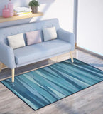 Modern coastal blue abstract area rug on wood floor beside light blue sofa with pastel cushions in bright room