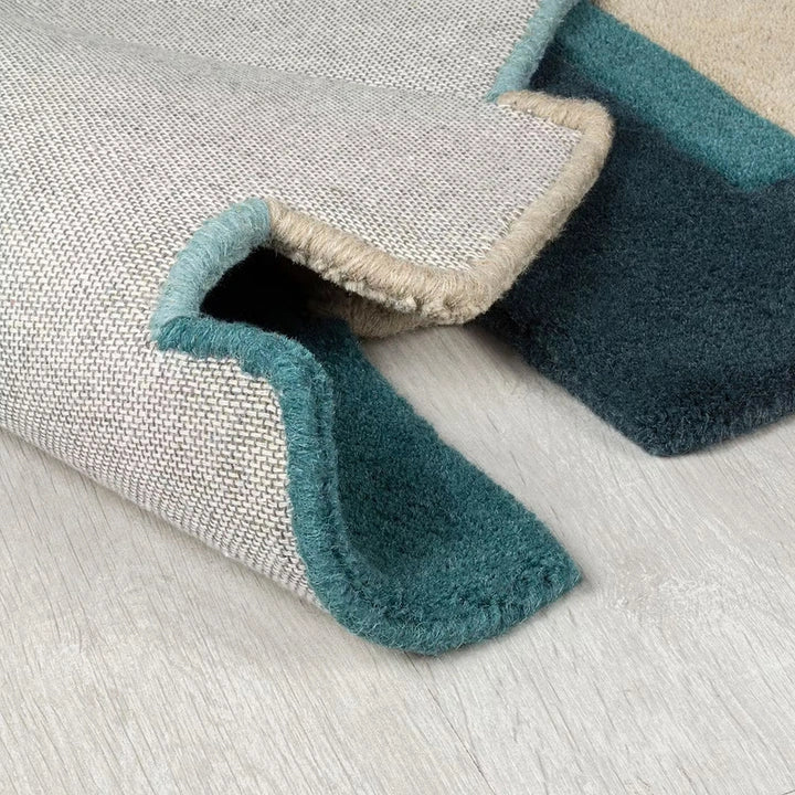 Close-up of a textured rug with a blue border on a light wooden floor.