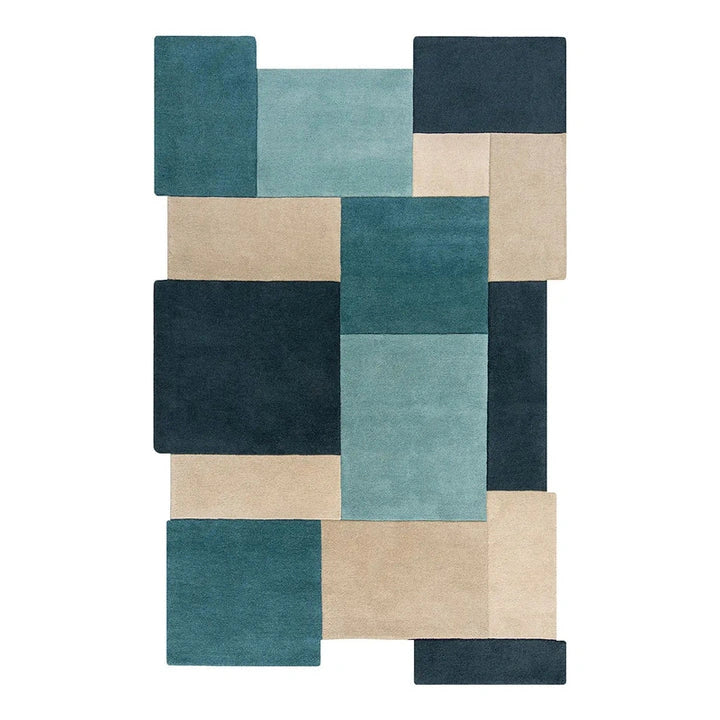 A modern geometric area rug featuring a block pattern in shades of teal, navy blue, and beige, shown flat against a solid white background.