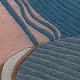 Close-up of a textured contemporary abstract thread design rug with blue, pink, gray, and brown colors