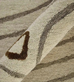 Close-up of hand-tufted Cosmic Still rug in beige and brown tones with abstract curved patterns