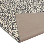 Cream and black geometric floral patterned rug with folded corner showing textured backing