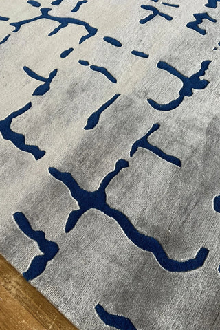 Hand-knotted abstract wool rug with cream background and blue accents.