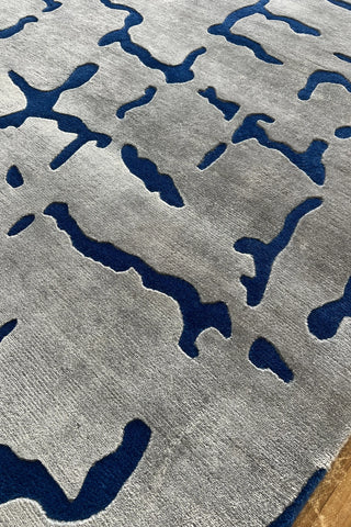 Artistic wool rug with geometric crackle-style blue accents on cream.
