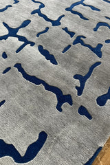 Artistic wool rug with geometric crackle-style blue accents on cream.