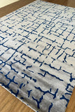 Modern cream wool rug with blue abstract crackle pattern on wooden floor