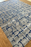 Grey wool rug with blue abstract crackle pattern on wooden floor