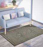 Elegant dark ornate rug with intricate patterns under a light blue modern sofa in a bright living room