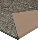 Dark ornate rug with intricate floral and geometric patterns, beige backing fabric visible