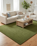 Deep green solid minimalist area rug with a hand-tufted finish, placed in a living room to create a calm, modern, and refined interior accent